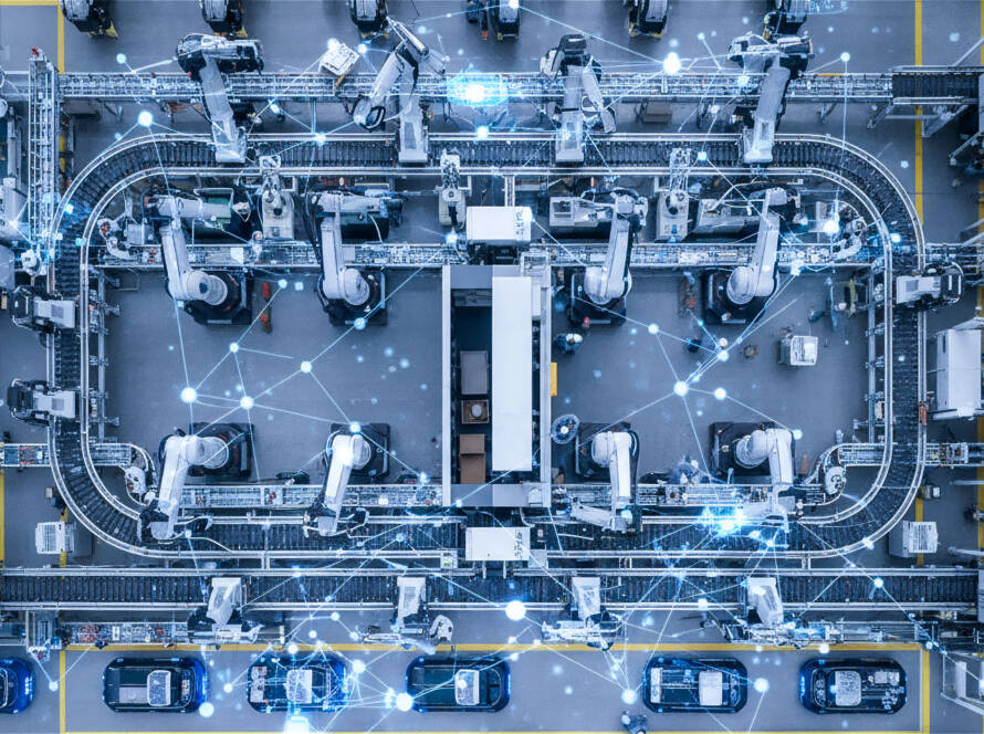 High-angle view of modern automated factory with robotic arms, conveyors, AGVs, human workers, and glowing light blue data connections.